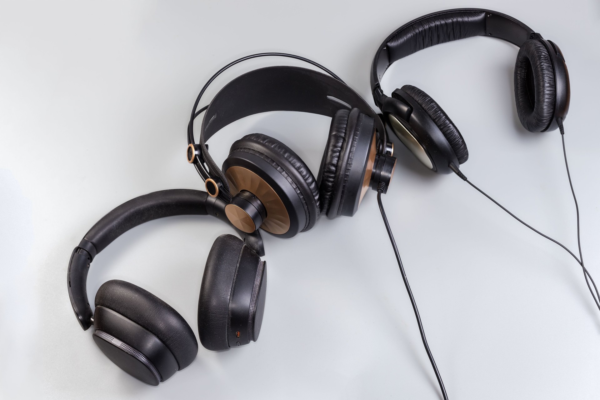 Various wired and wireless full size headphones on gray background